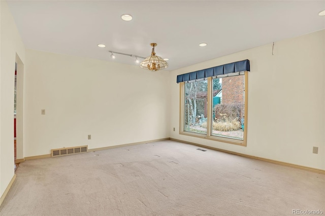 spare room with carpet floors, an inviting chandelier, baseboards, and visible vents