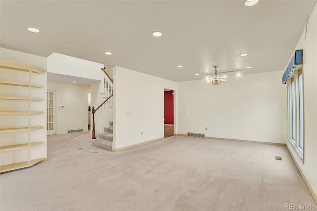 empty room featuring visible vents, light colored carpet, stairway, an inviting chandelier, and recessed lighting