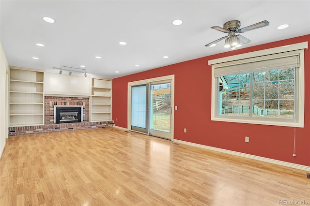 unfurnished living room with light wood finished floors, a wealth of natural light, and baseboards