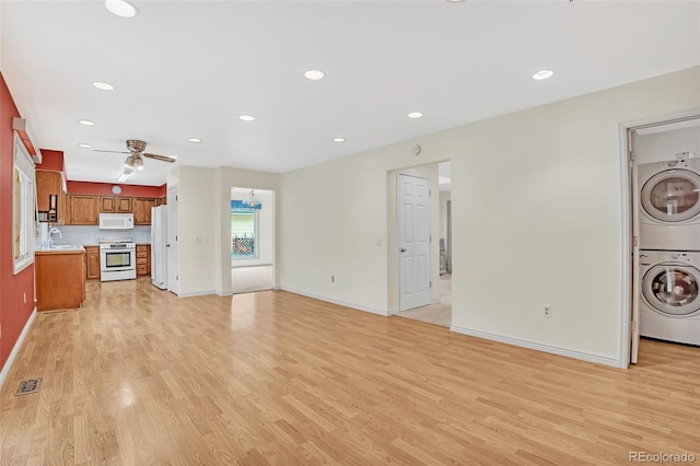 unfurnished living room featuring light wood-style flooring, recessed lighting, a sink, visible vents, and stacked washing maching and dryer