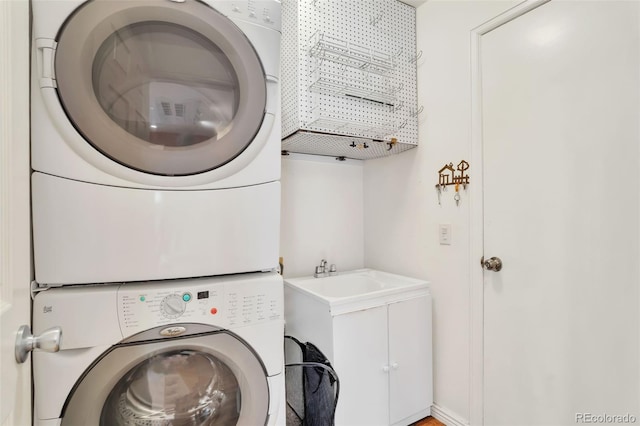 clothes washing area with stacked washer and dryer and a sink