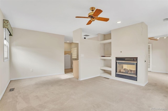 unfurnished living room with built in features, light colored carpet, visible vents, a multi sided fireplace, and baseboards