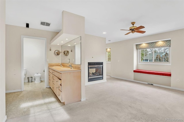 bathroom with a multi sided fireplace, vanity, baseboards, visible vents, and a bidet