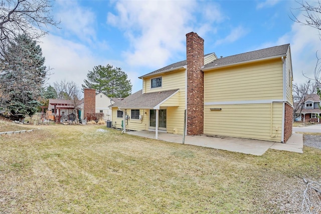 back of house featuring a yard, a chimney, and a patio area