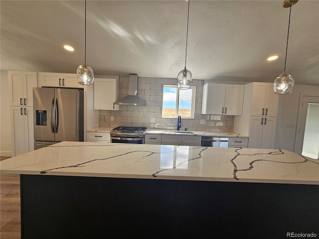 kitchen with a kitchen island, wall chimney exhaust hood, stainless steel appliances, light stone countertops, and white cabinetry