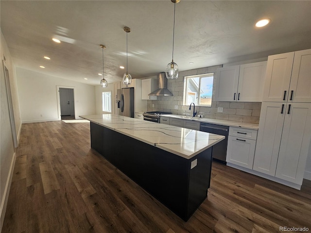 kitchen with a center island, appliances with stainless steel finishes, wall chimney range hood, and white cabinetry