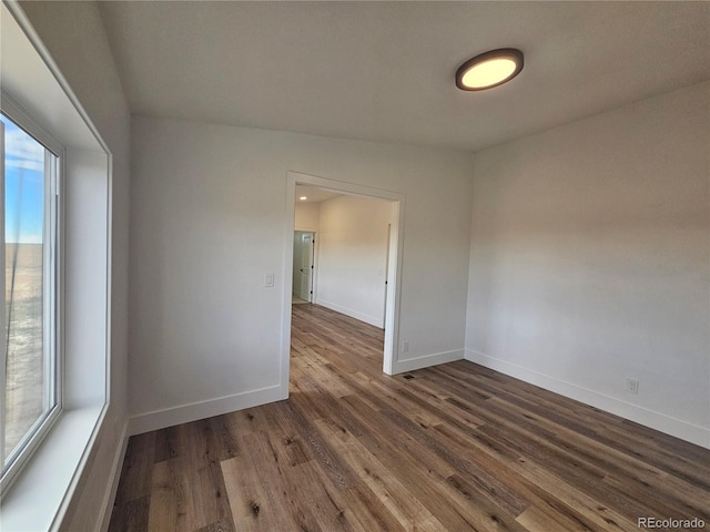 empty room with a healthy amount of sunlight, vaulted ceiling, and dark hardwood / wood-style floors