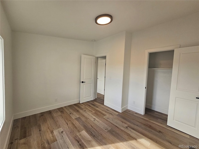 unfurnished bedroom featuring wood-type flooring and a closet