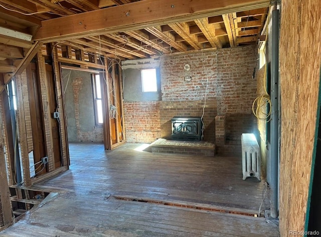 interior space featuring brick wall, radiator heating unit, hardwood / wood-style floors, and a wood stove