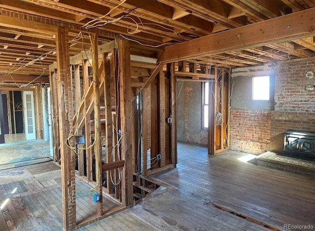 miscellaneous room featuring hardwood / wood-style floors, brick wall, and a wood stove