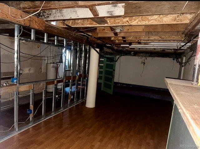 basement featuring wood-type flooring and water heater