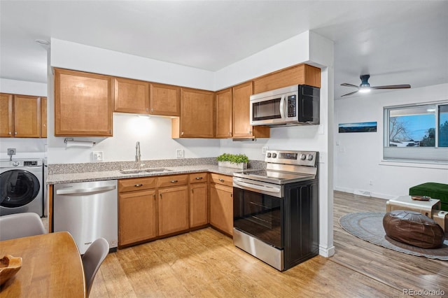 kitchen with sink, light wood-type flooring, appliances with stainless steel finishes, ceiling fan, and washer / clothes dryer