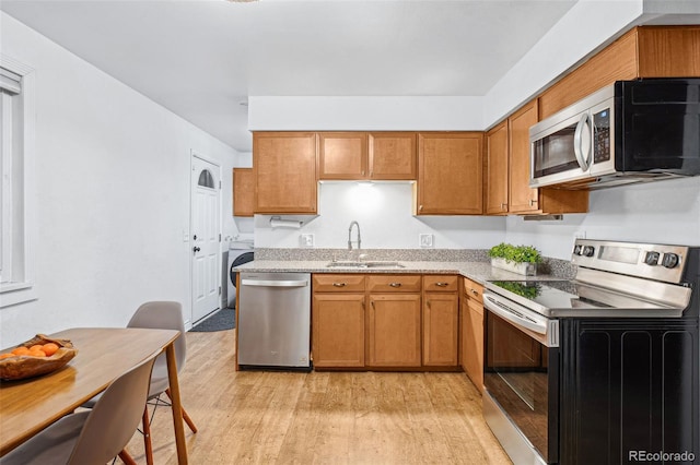 kitchen with appliances with stainless steel finishes, sink, and light hardwood / wood-style floors