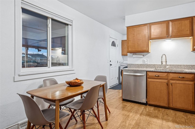 kitchen with sink, light hardwood / wood-style flooring, baseboard heating, light stone countertops, and stainless steel dishwasher