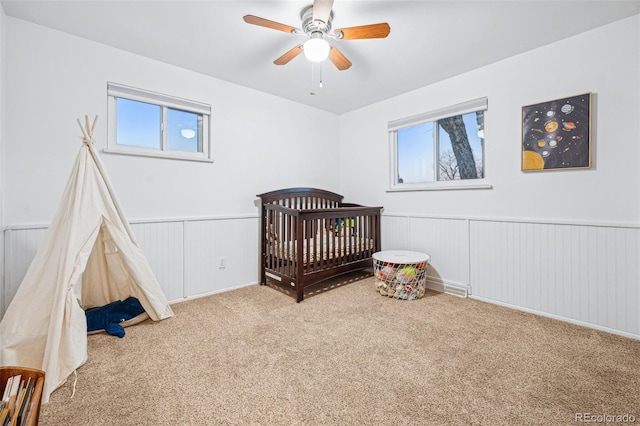 bedroom featuring carpet floors, a nursery area, and ceiling fan