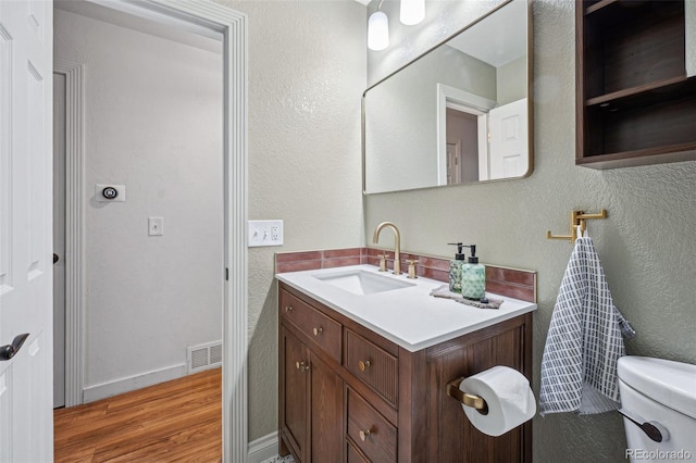 bathroom featuring vanity, wood-type flooring, and toilet