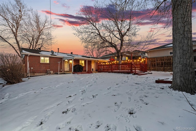 snow covered back of property with a wooden deck