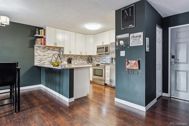 kitchen with white cabinetry, appliances with stainless steel finishes, dark hardwood / wood-style flooring, and kitchen peninsula