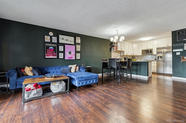 living room with a textured ceiling, a notable chandelier, and dark hardwood / wood-style floors