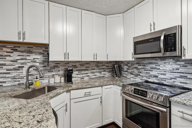 kitchen with decorative backsplash, white cabinets, a textured ceiling, sink, and stainless steel appliances