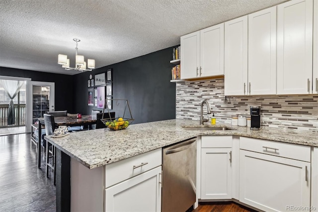 kitchen featuring dark hardwood / wood-style flooring, white cabinetry, stainless steel dishwasher, decorative light fixtures, and sink