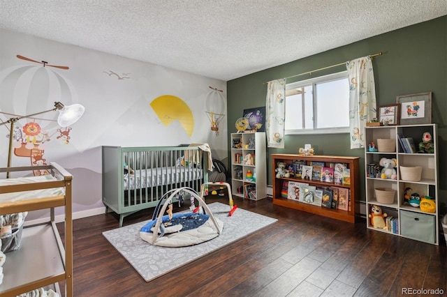 bedroom featuring a nursery area, a textured ceiling, and dark hardwood / wood-style flooring