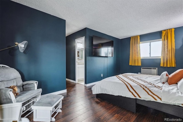 bedroom featuring an AC wall unit, a textured ceiling, dark hardwood / wood-style floors, and ensuite bath