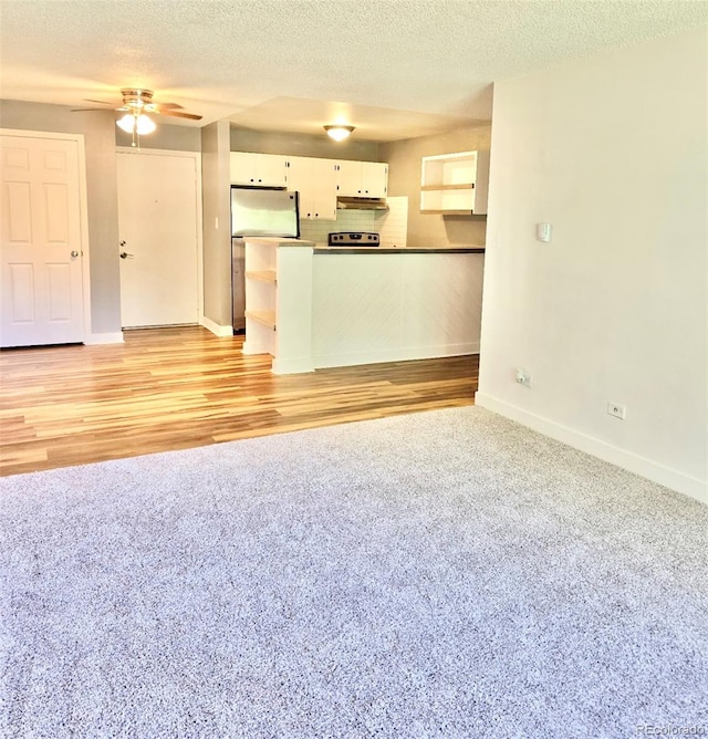 unfurnished living room featuring light hardwood / wood-style flooring, a textured ceiling, and ceiling fan