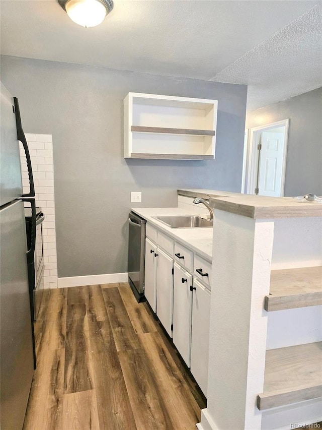 kitchen with sink, stainless steel appliances, dark hardwood / wood-style floors, white cabinets, and a textured ceiling