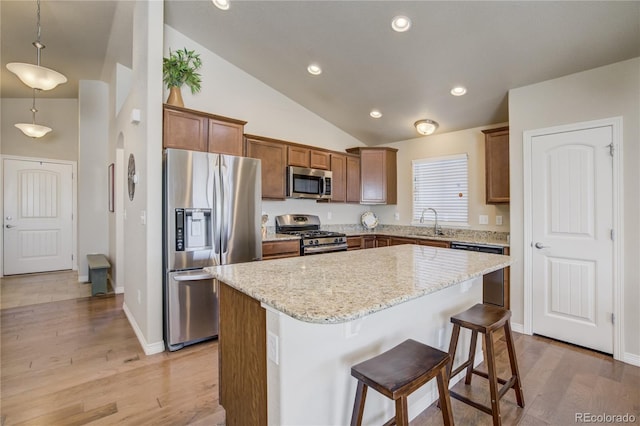 6812 Indian Paintbrush St, Frederick, CO 80530 - kitchen with appliances with stainless steel finishes, lofted ceiling, a sink, a center island, and light wood-type flooring