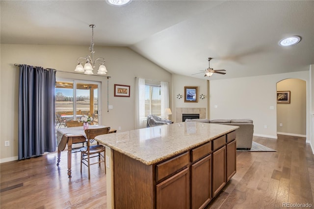 6812 Indian Paintbrush St, Frederick, CO 80530 - kitchen featuring a tiled fireplace, lofted ceiling, ceiling fan, wood finished floors, and arched walkways