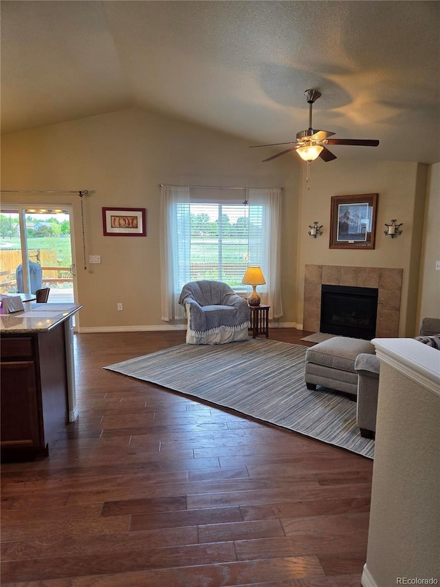6812 Indian Paintbrush St, Frederick, CO 80530 - living room with lofted ceiling, dark wood-style flooring, a ceiling fan, a tiled fireplace, and baseboards