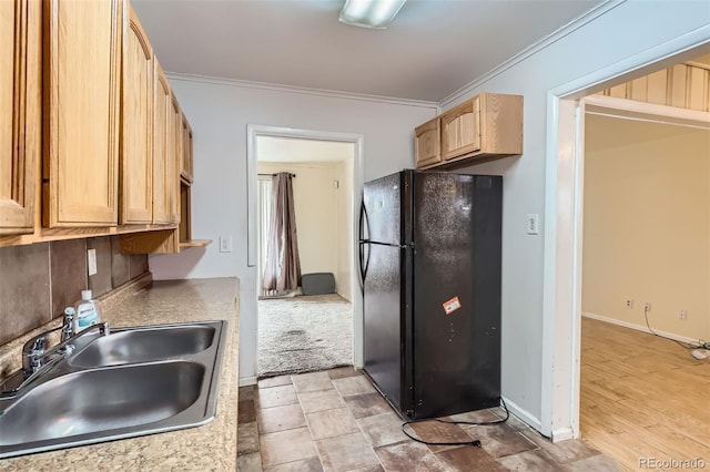 kitchen featuring black refrigerator, light wood-type flooring, ornamental molding, and sink