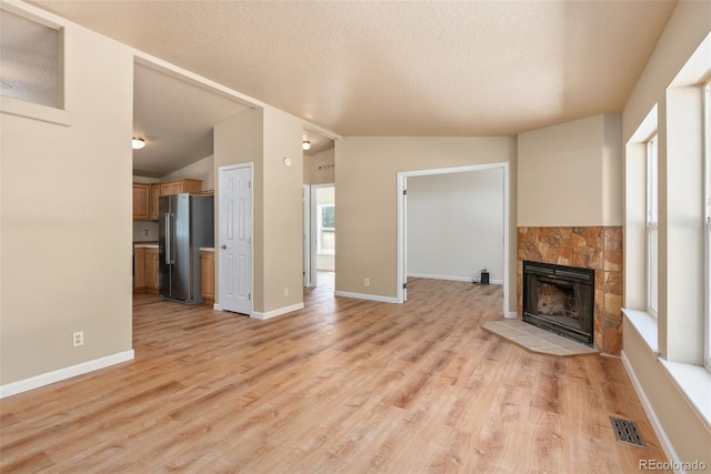 140 Beaver Rd, Idaho Springs, CO 80452 - unfurnished living room with lofted ceiling, light wood-style flooring, a fireplace, a textured ceiling, and baseboards