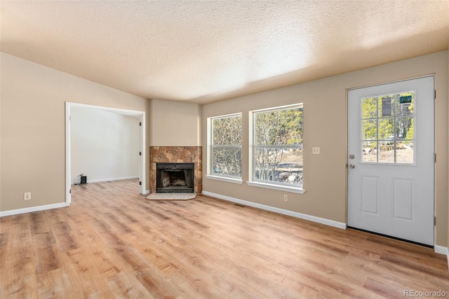 140 Beaver Rd, Idaho Springs, CO 80452 - unfurnished living room with light wood-style floors, baseboards, a tile fireplace, and a textured ceiling