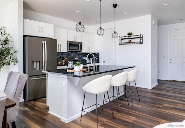 kitchen with tasteful backsplash, decorative light fixtures, a kitchen breakfast bar, stainless steel appliances, and white cabinets