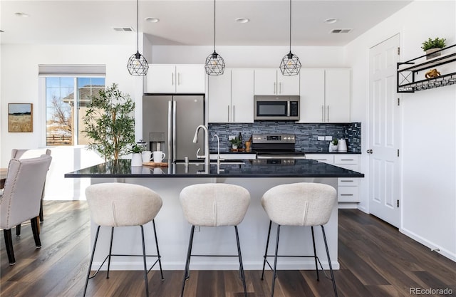 kitchen with appliances with stainless steel finishes, sink, hanging light fixtures, and white cabinets