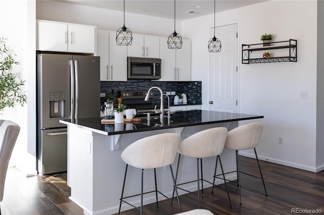 kitchen featuring white cabinetry, backsplash, a kitchen breakfast bar, stainless steel appliances, and an island with sink