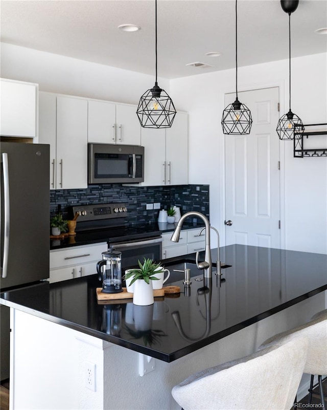 kitchen featuring white cabinetry, appliances with stainless steel finishes, decorative light fixtures, and decorative backsplash