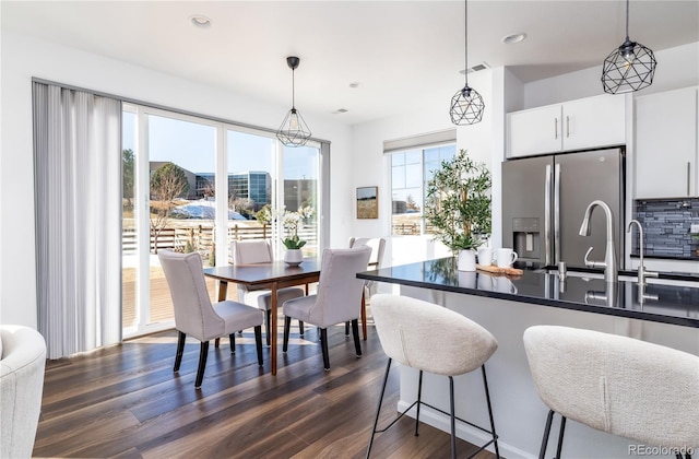 kitchen with white cabinetry, stainless steel fridge with ice dispenser, pendant lighting, and dark hardwood / wood-style flooring