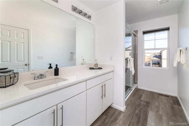 bathroom with walk in shower, vanity, and hardwood / wood-style floors