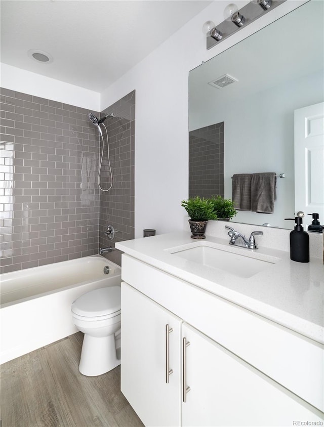 full bathroom featuring vanity, toilet, tiled shower / bath combo, and hardwood / wood-style floors