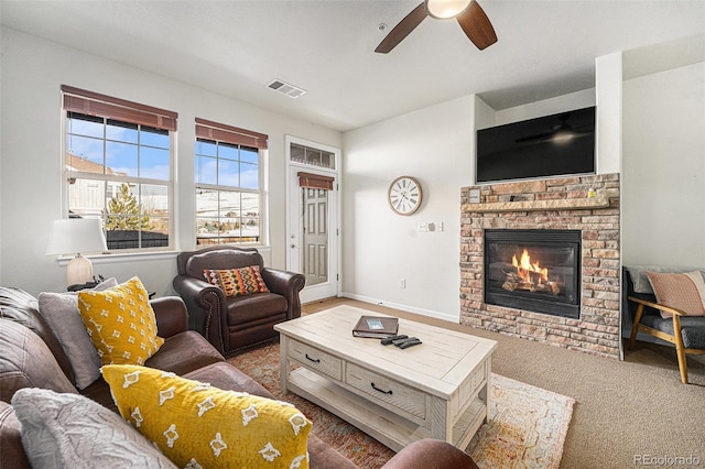 carpeted living area with ceiling fan, a fireplace, visible vents, and baseboards