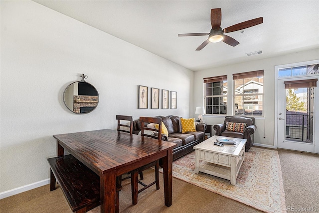 carpeted living room featuring a ceiling fan, visible vents, and baseboards