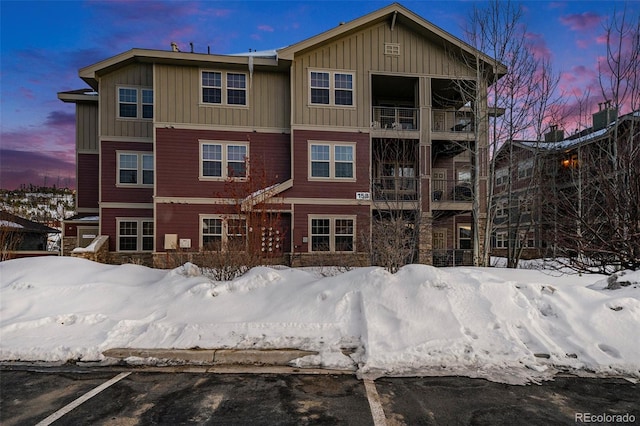 snow covered back of property featuring board and batten siding