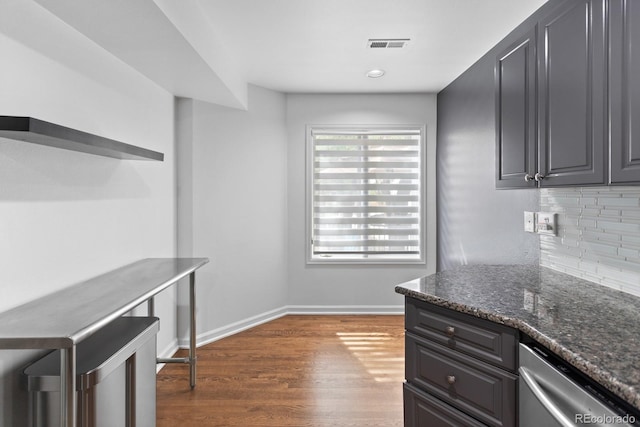 kitchen with tasteful backsplash, dark stone counters, dark hardwood / wood-style flooring, and dishwasher