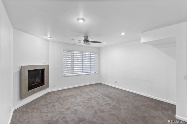 unfurnished living room featuring a tiled fireplace, carpet floors, and ceiling fan