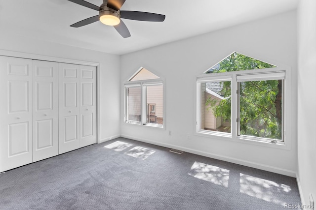 unfurnished bedroom featuring multiple windows, a closet, ceiling fan, and carpet