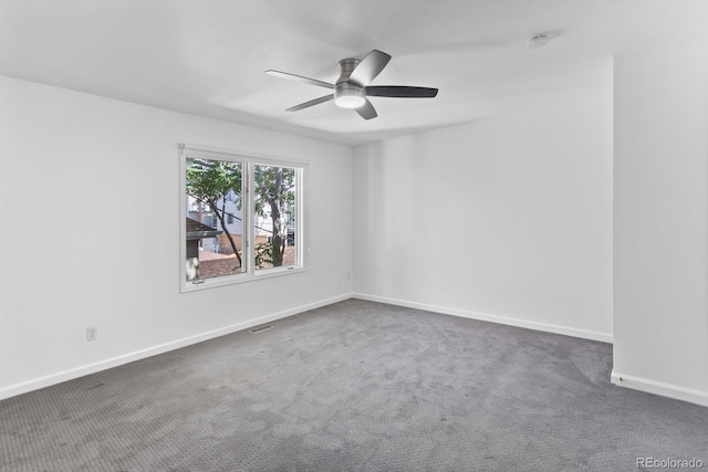 spare room featuring ceiling fan and dark colored carpet