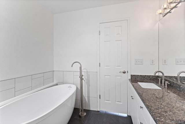 bathroom with tile patterned floors, an inviting chandelier, tile walls, vanity, and a washtub